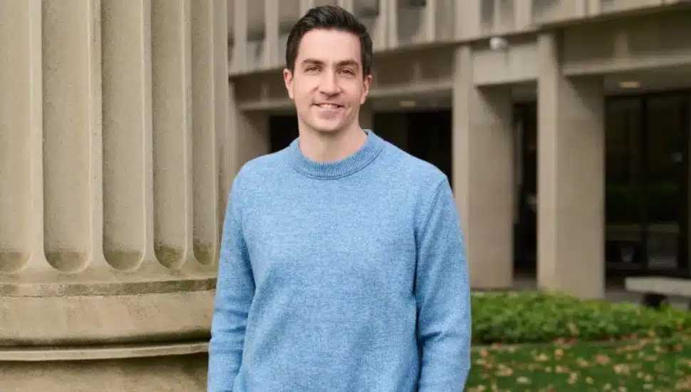 John O'Brien in a blue sweater in front of old courthouse.