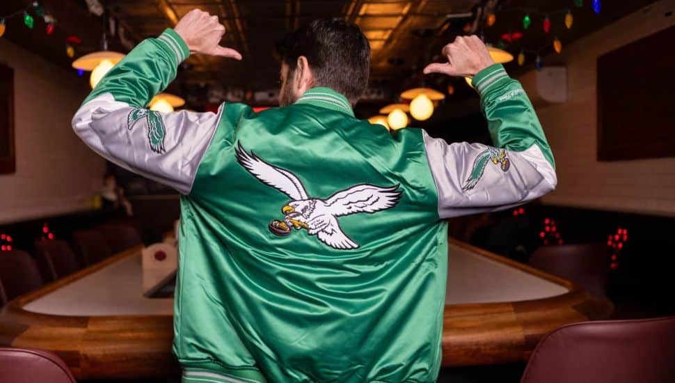 Man points to back of kelly green Philadelphia Eagles jacket.