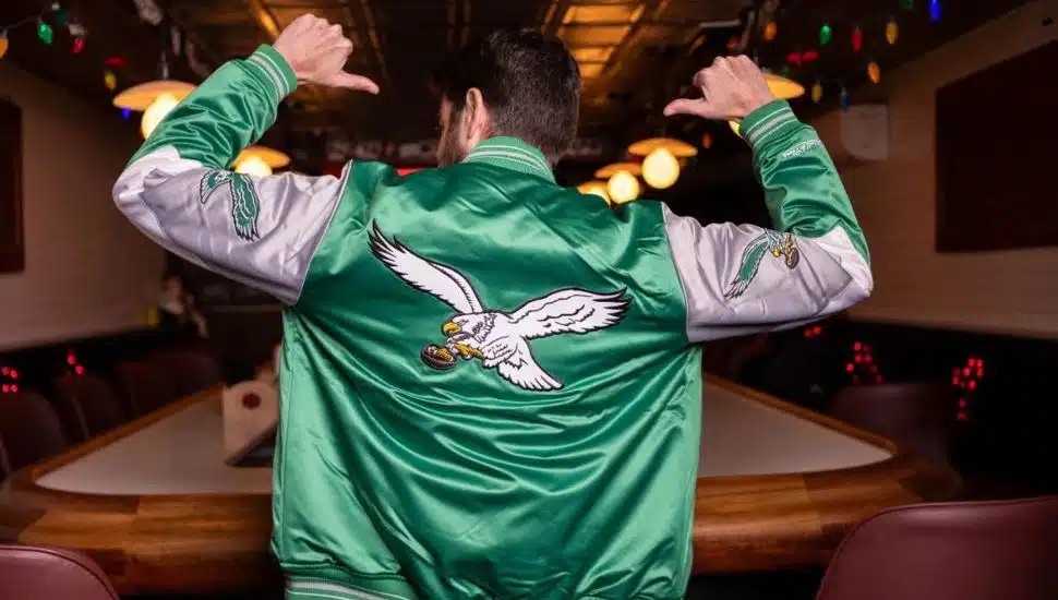 Man points to back of kelly green Philadelphia Eagles jacket.