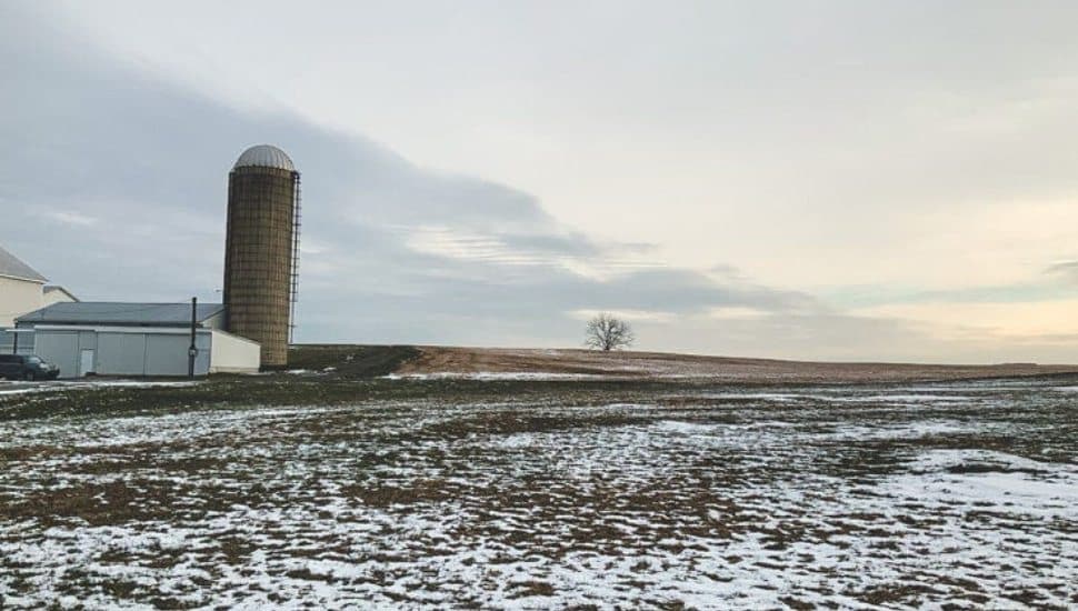 A silo along Lancaster farmland covered in light snow.