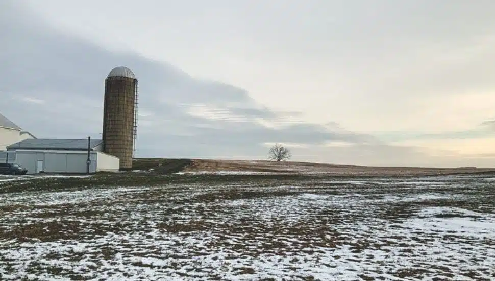 A silo along Lancaster farmland covered in light snow.