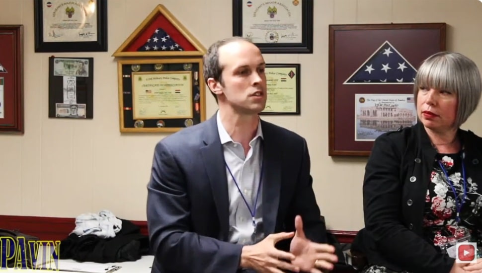 Tanner Rouse talking in an office with a woman next to him.