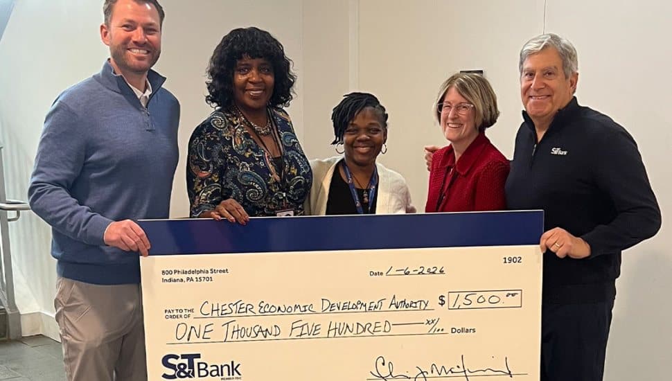 Group of S&T Bank representatives and Chester Economic Development Authority members holding a large $1,500 donation check inside a community building.