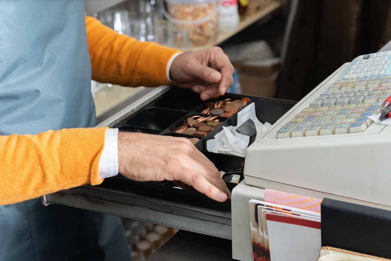 Person pulling change out of a cash drawer.