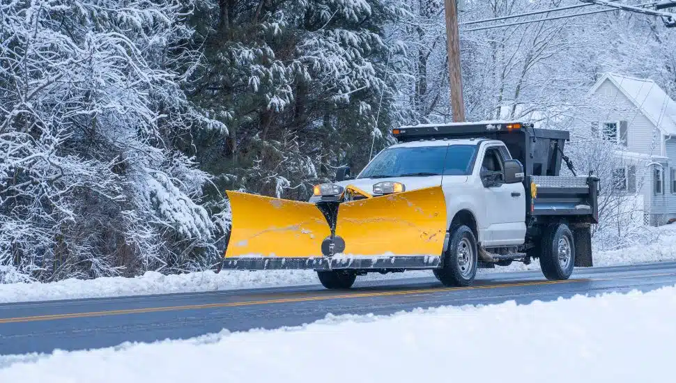 Snow plow on road in snowy weather.