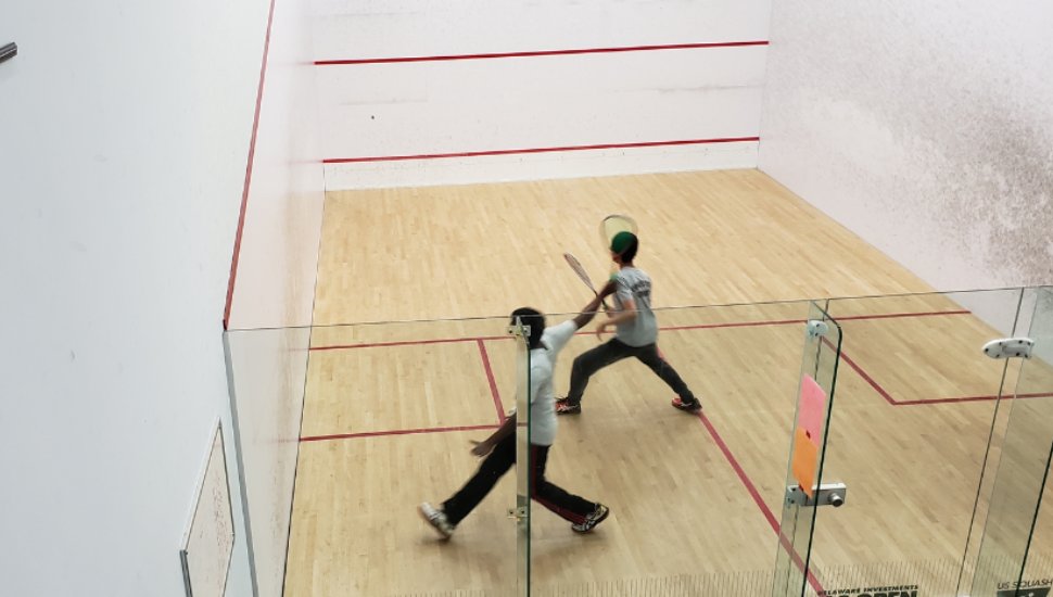 Two athletes on a squash court at Berwyn Squash & Fitness Club.