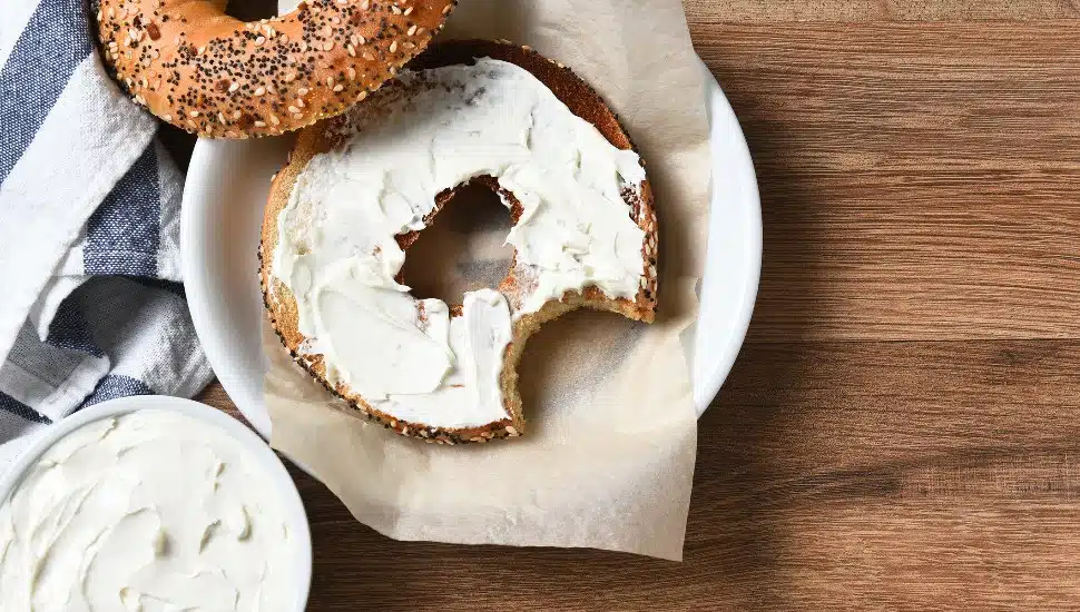 A bagel topped with cream cheese on a plate.