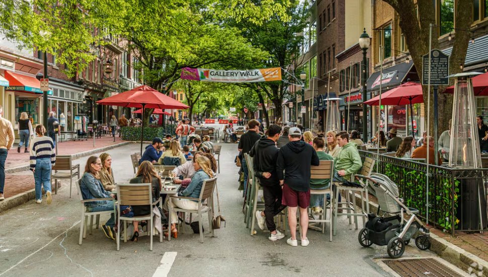 Visitors seated at tables and walking along sidewalks in downtown West Chester.