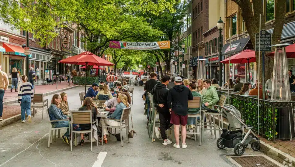 Visitors seated at tables and walking along sidewalks in downtown West Chester.