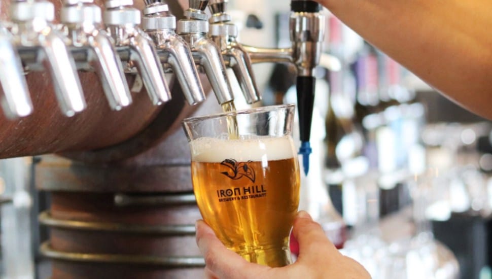 Person pouring Iron Hill beer from tap.
