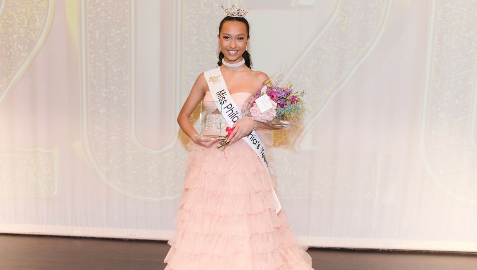 Ksenya Wong with award wearing light pink dress.
