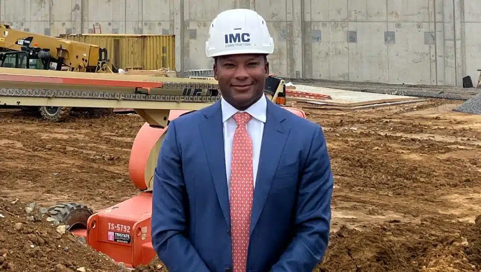 Mike Lloyd at construction site wearing suit and hard hat.