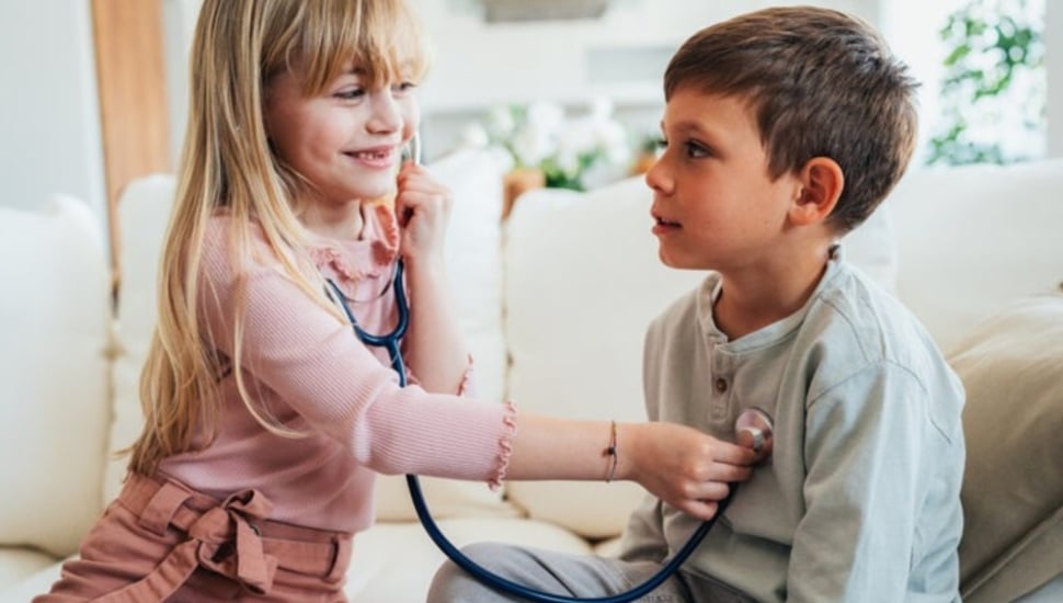 Two kids play with a stethoscope.