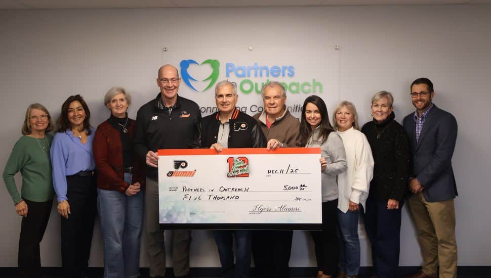 Members of the Philadelphia Flyers Alumni Association present a $5,000 donation check to Partners in Outreach during the 12 Days of Giving campaign.