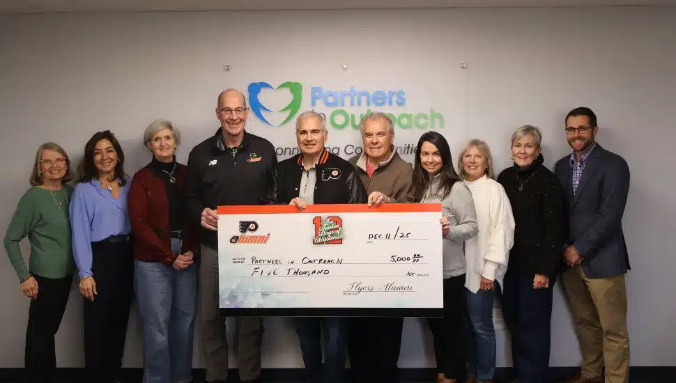 Members of the Philadelphia Flyers Alumni Association present a $5,000 donation check to Partners in Outreach during the 12 Days of Giving campaign.