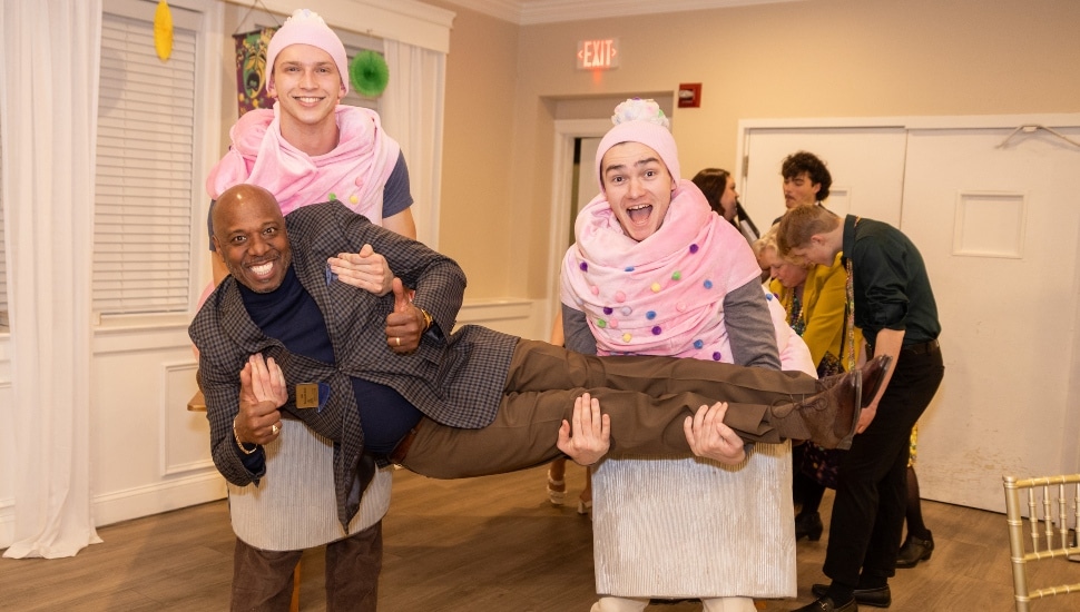Two young wearing cupcake costumes hold a guest at Sweet Charity.