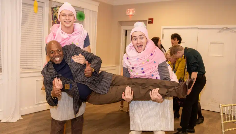 Two young wearing cupcake costumes hold a guest at Sweet Charity.