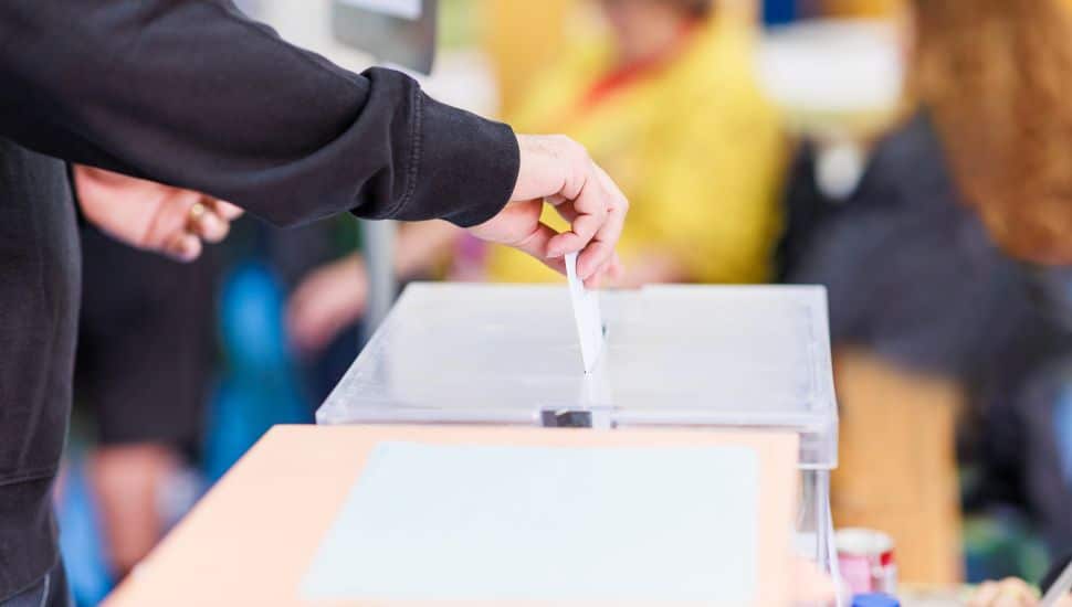 Person putting ballot into box.