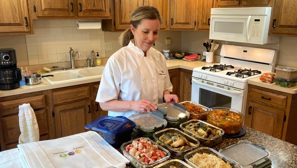 A woman chef prepares a meal inside a residential kitchen.