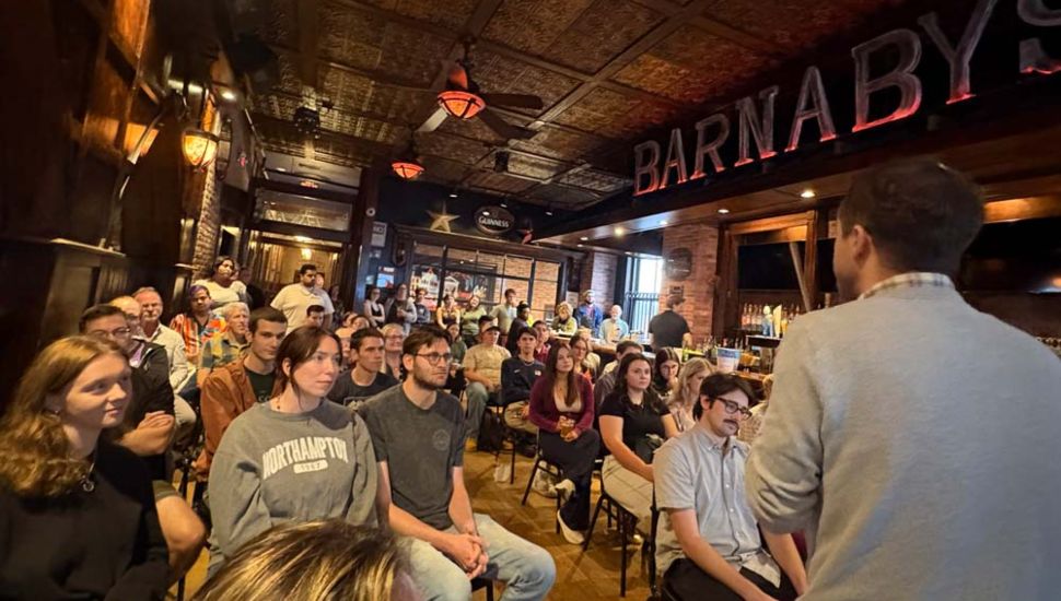 Audience members seated inside Barnaby’s Restaurant in West Chester listen to a West Chester University speaker during a Science on Tap presentation, with exposed brick walls and restaurant signage visible in the background.