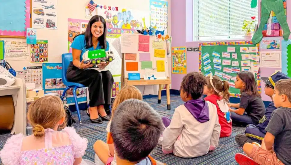 Teacher reading a book to young students.