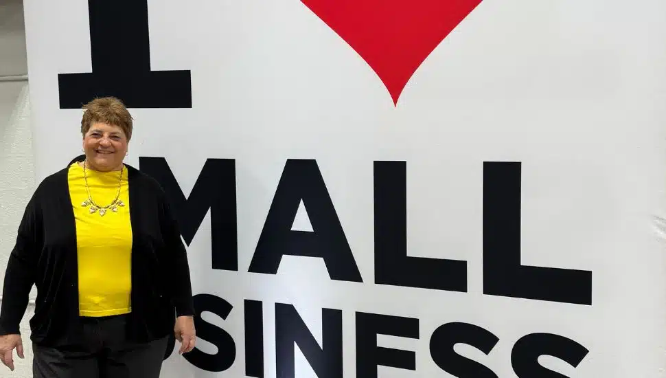 Lynne Williams in front of the I live Small Business sign.