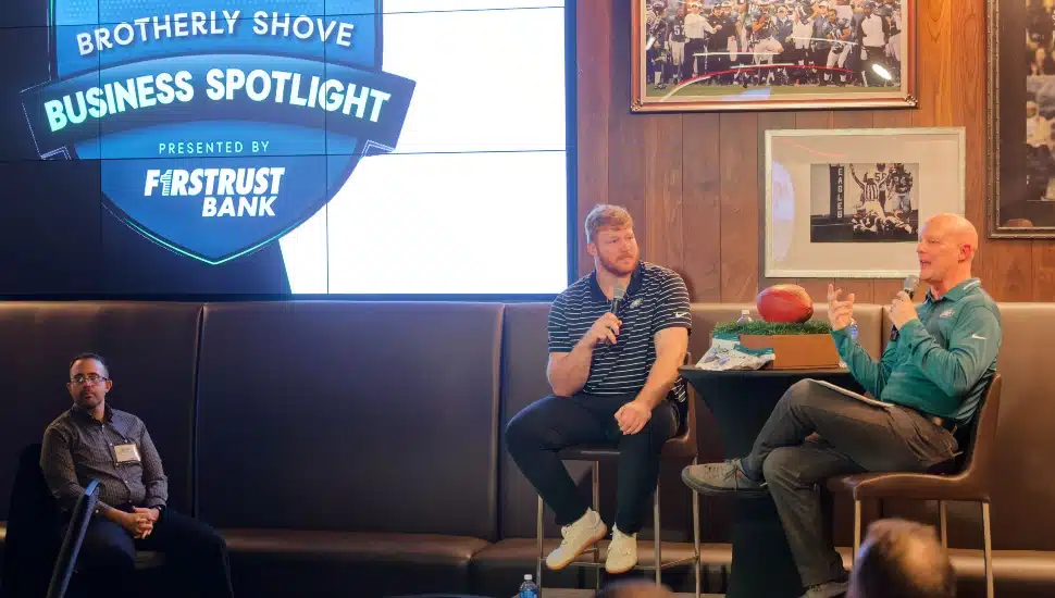Two men lead discussion on stage at event.