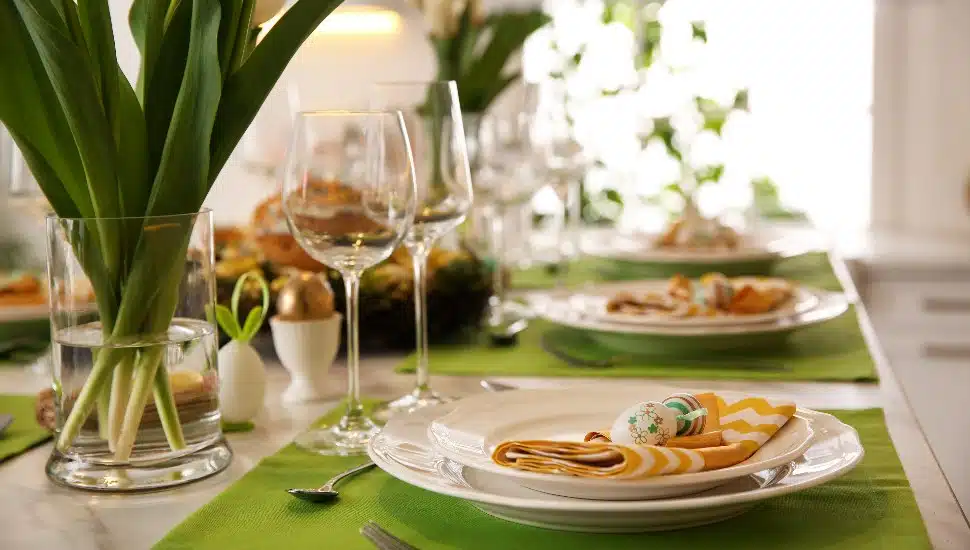 Wine glasses, table flowers, plates, and cutlery set for a festive Easter meal.
