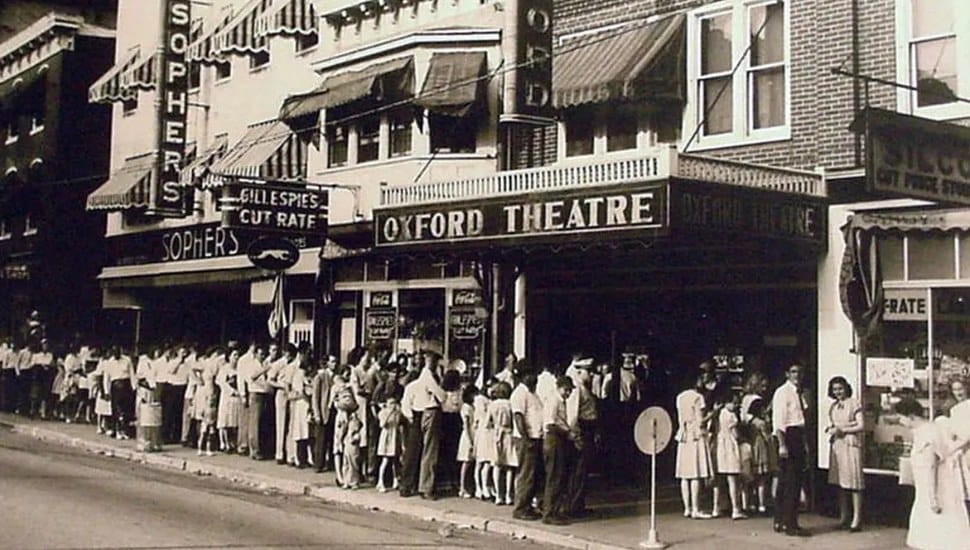 A black and white photo of the exterior of the historic Oxford Theatre and a surrounding crowd.