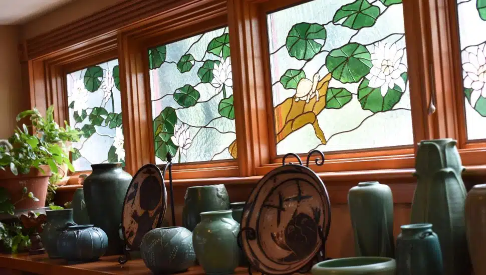 A green and white stained glass window above a shelf of homewares.