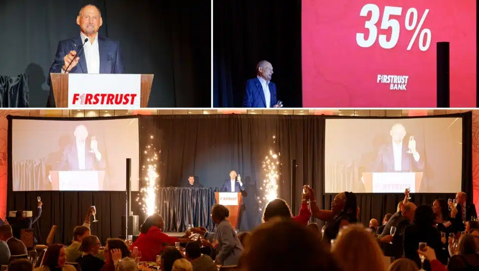 Bank chairman addresses employees from podium and raises his glass amidst fireworks.