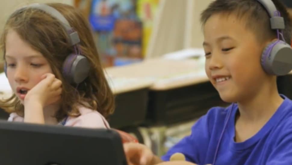 Two students, a boy and a girl, listen on headphones during class at Swarthmore-Rutledge Elementary School in the Swarthmore-Wallingford School District.