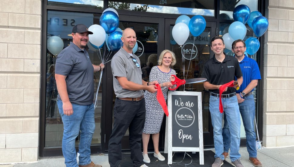 Group of people cut ribbon for opening of Bella Vita.