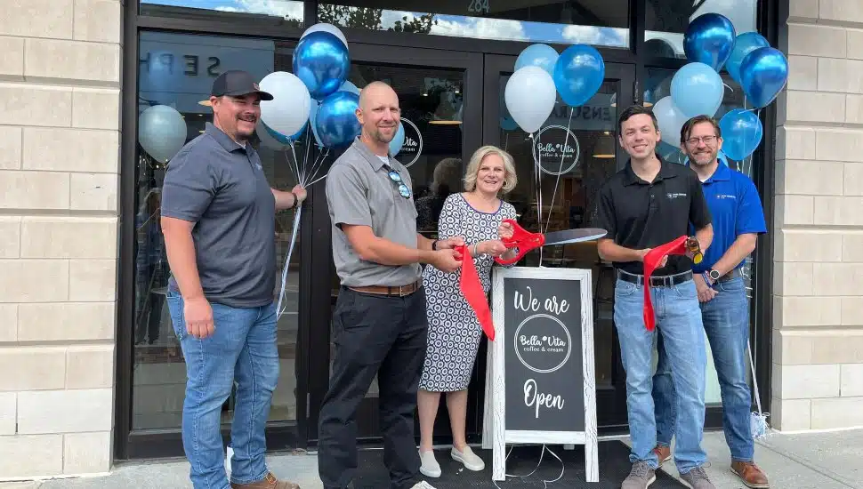Group of people cut ribbon for opening of Bella Vita.