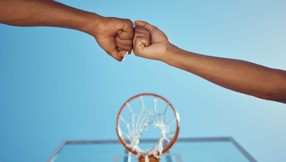 Hands of basketball friends or team fist bump at game training and practice match at basketball court. Competitive athlete people in unity, solidarity and union play together sports hobby for fitness.