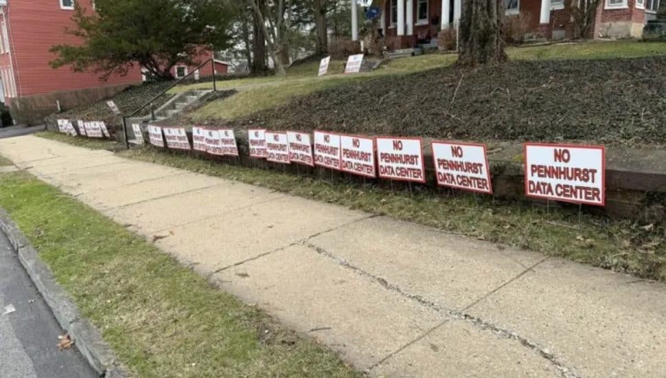 Line of "No Pennhurst Data Center" signs along sidewalk.