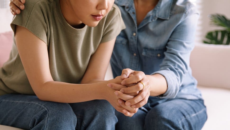 Adult comforts young teen, mother/daughter relationship.