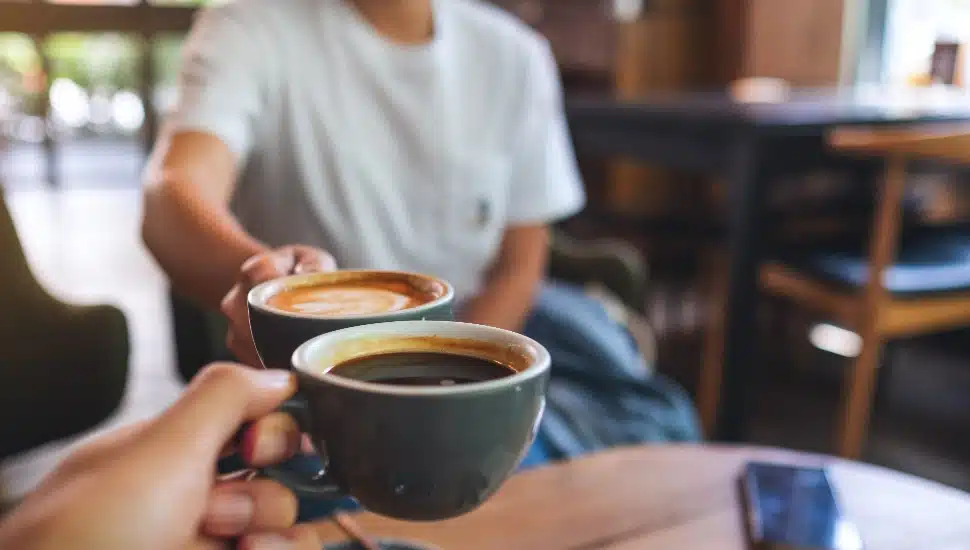 Two people sharing a cup of coffee at a coffee shop.