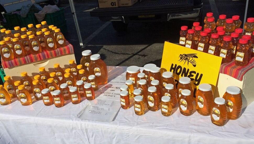 Rows of Jeff Bryer Apiary honey available at an outdoor market.