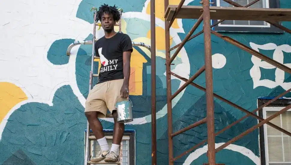 Noah Burns with scaffolding while painting the mural.