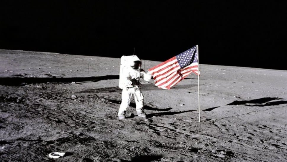 Astronaut Pete Conrad unfurling an American flag on his moonwalk.