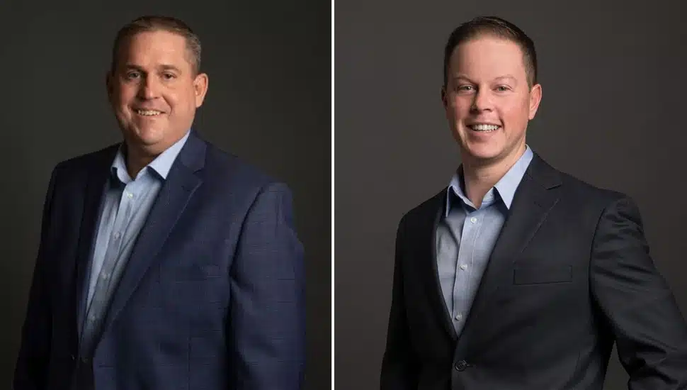 Headshots of two male business executives in dark suits and open-collared shirts.