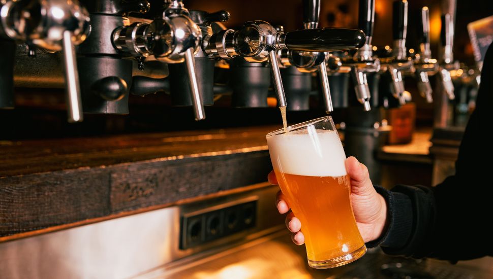 Person pouring beer from tap into glass.