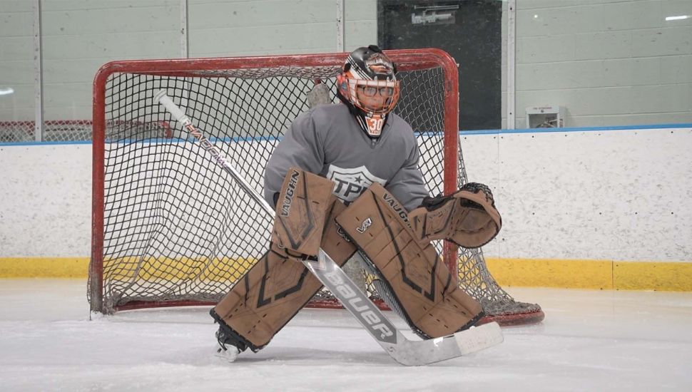 Hockey player Brayden Baldwin practicing goaltending on the ice.
