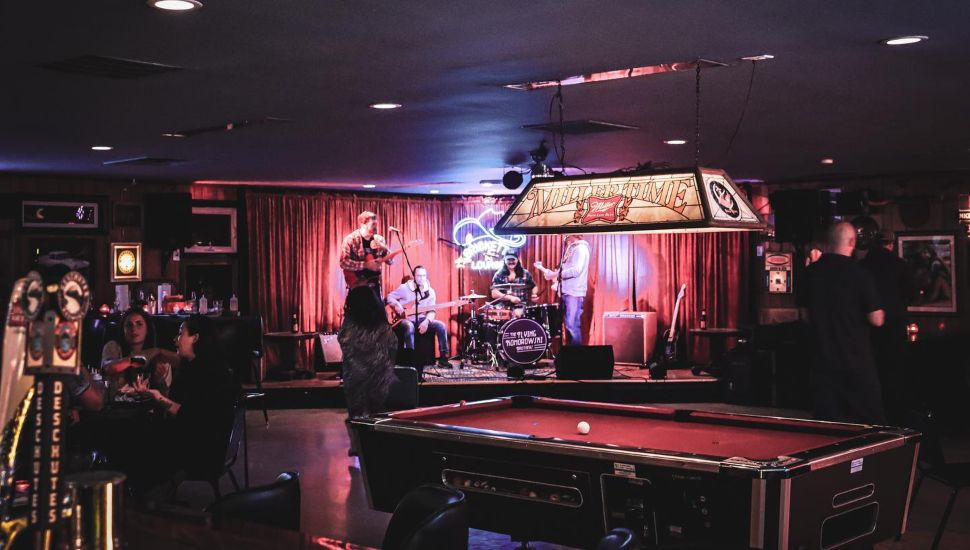 Brickette Lounge dim interior with pool table, live band, and people drinking.