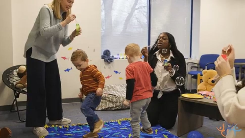 CCRES staff members share a moment with young children in movement and blowing bubbles.
