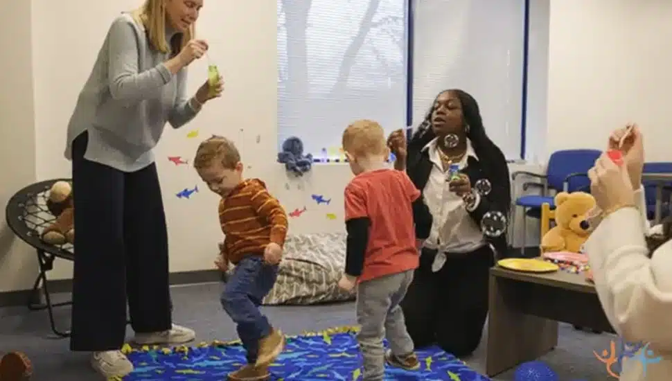 CCRES staff members share a moment with young children in movement and blowing bubbles.
