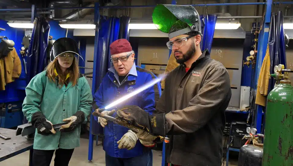 Instructor teaches welding students.
