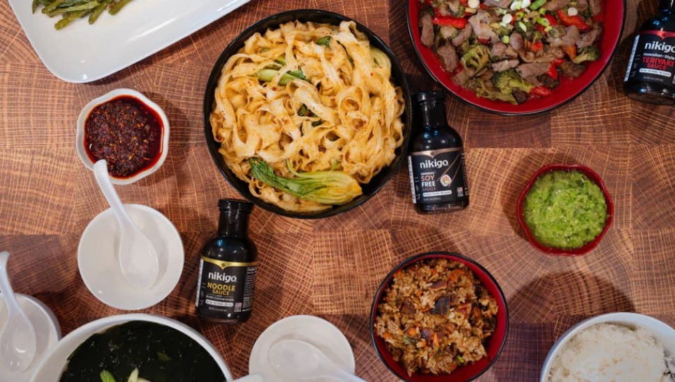 NIKIGO sauces on a table alongside several noodle dishes.