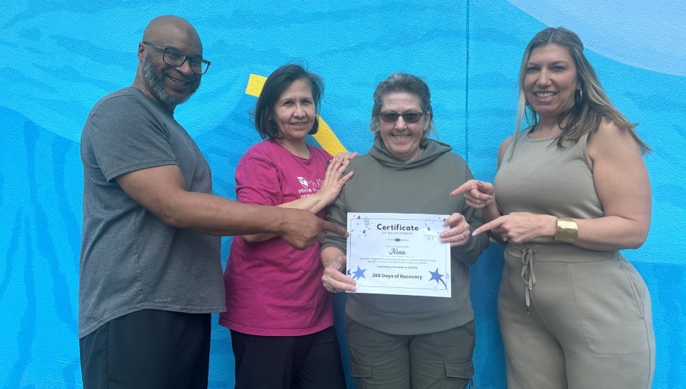 Nina holds a certificate recognizing a year in recovery, with the Safe Harbor staff who supported her.